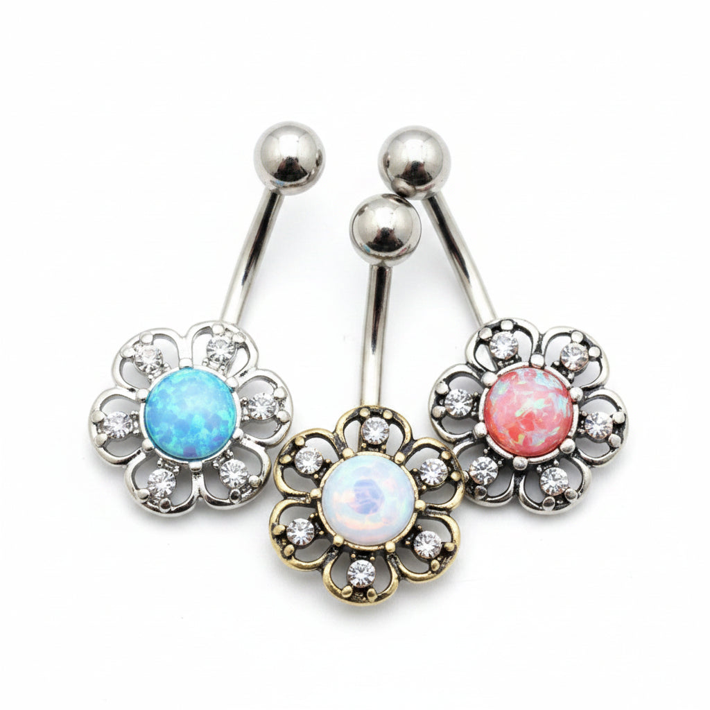 Three floral belly buttons with gemstones on a wooden surface